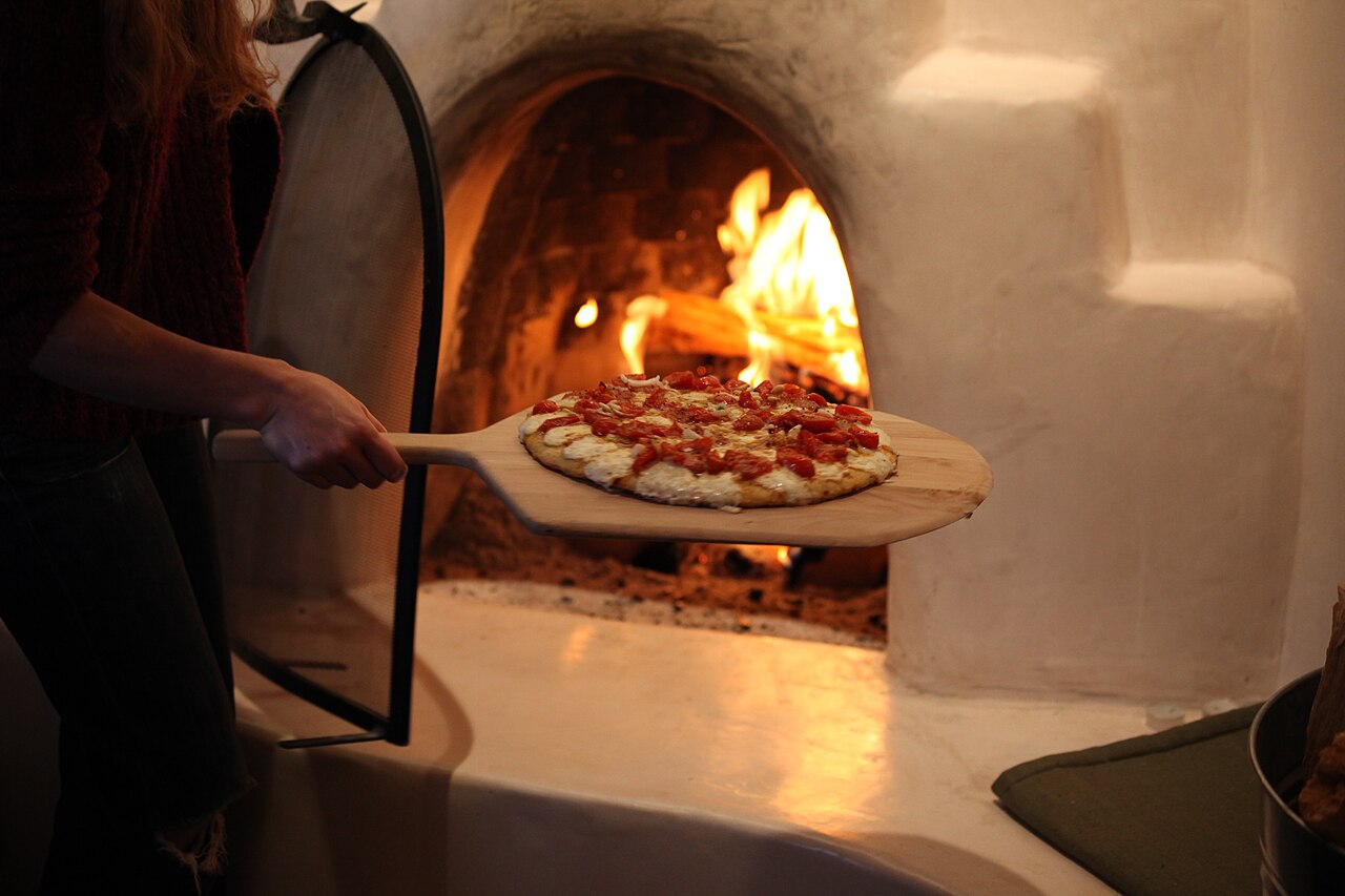 Pizza che entra nel forno a legna sulla pala